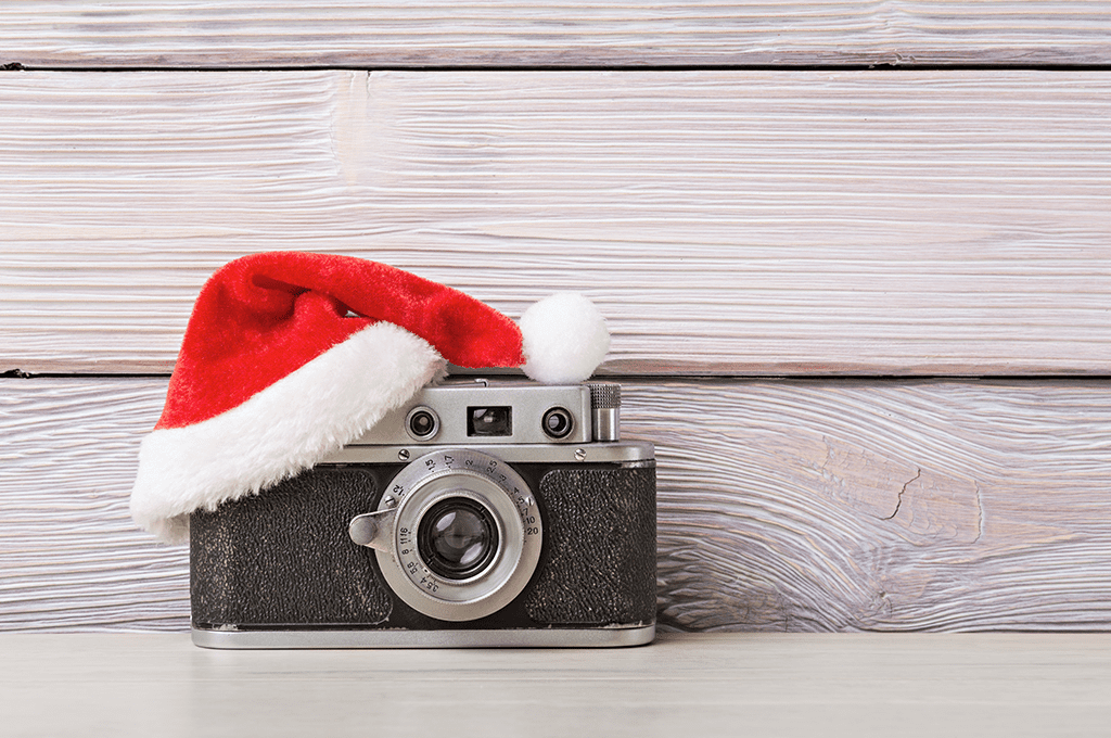 a black and silver vintage camera with a small Santa hat sitting on it