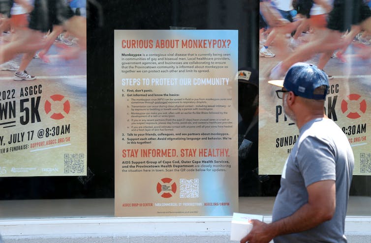 Person passing poster with health information on mpox