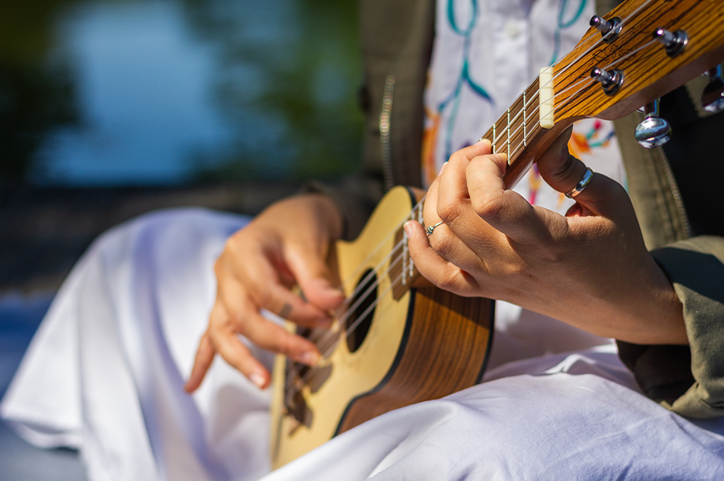 someone sat on the ground playing a ukelele