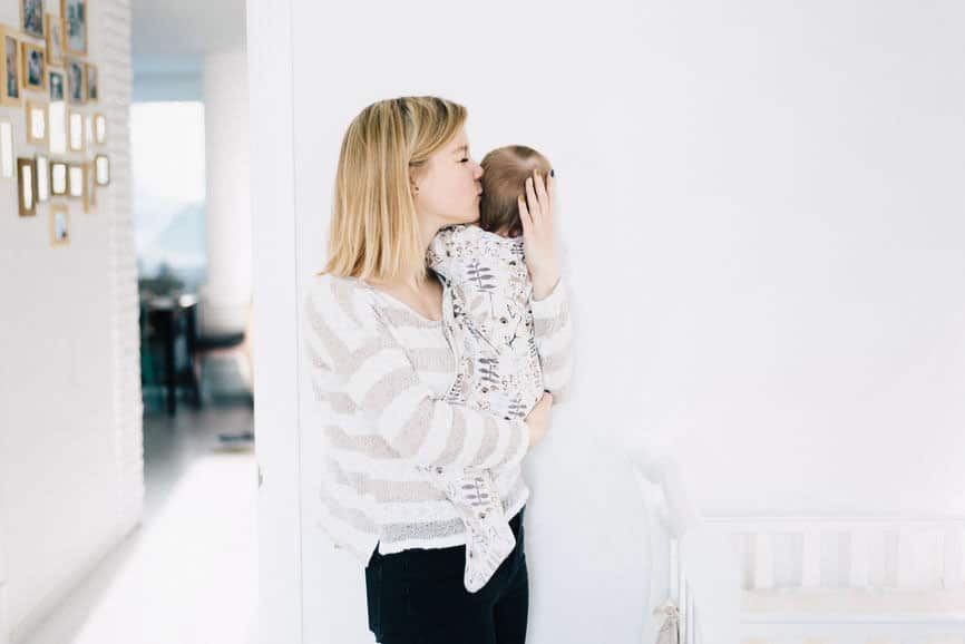 Mom holding a newborn in a beautiful white nursery