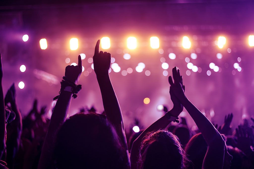 A crowd of people celebrating and partying with their hands in the air to an awesome DJ