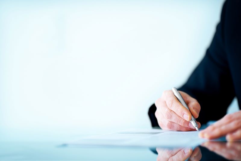 Business professional signing a piece of paper on a clear desk