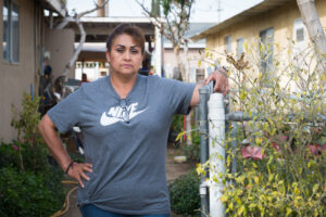 A photo shows a woman posing for a portrait outside by a fence.