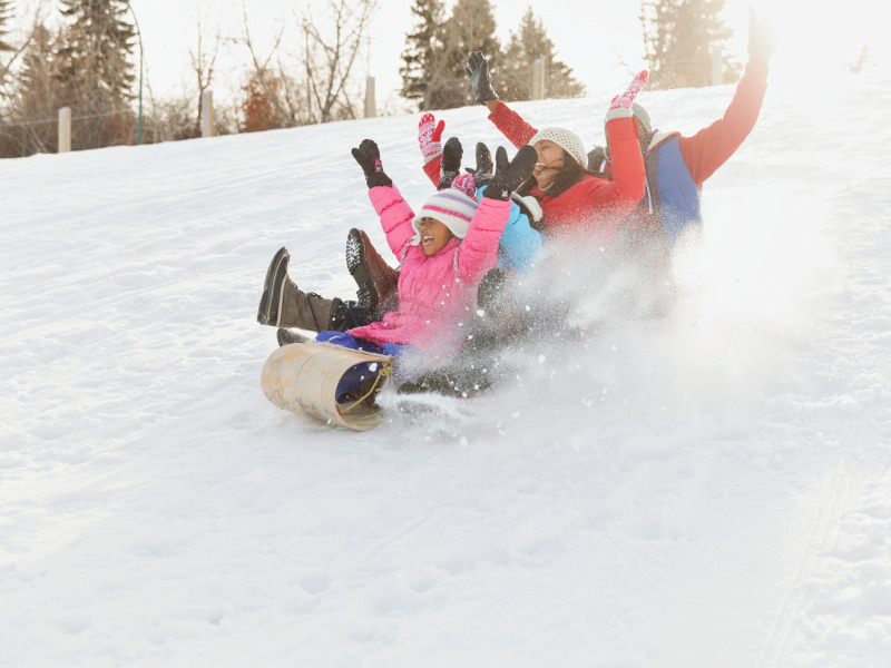 Excited family tobogganing in snow