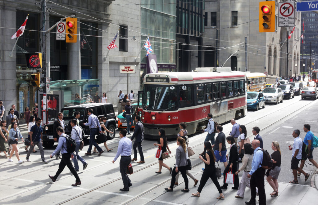 Toronto, Canada - August 15, 2016: People Crossing King Street at Yonge, Downtown Toronto, Ontario, Canada. Streetcar and pedestrians during afternoon rush hour in the Financial District, Downtown West neighbourhood.