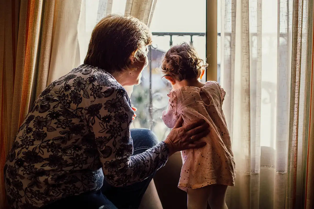 Grandmother and baby girl looking through a window together 