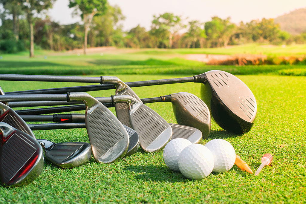 Golf balls and golf clubs in bag on green grass