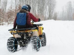 Two people riding on an ATV through the snow