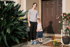 A photo of a mother and her young child outside of their home.