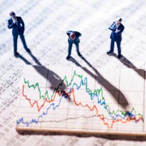 Three men looking down at a declining stock market numbers