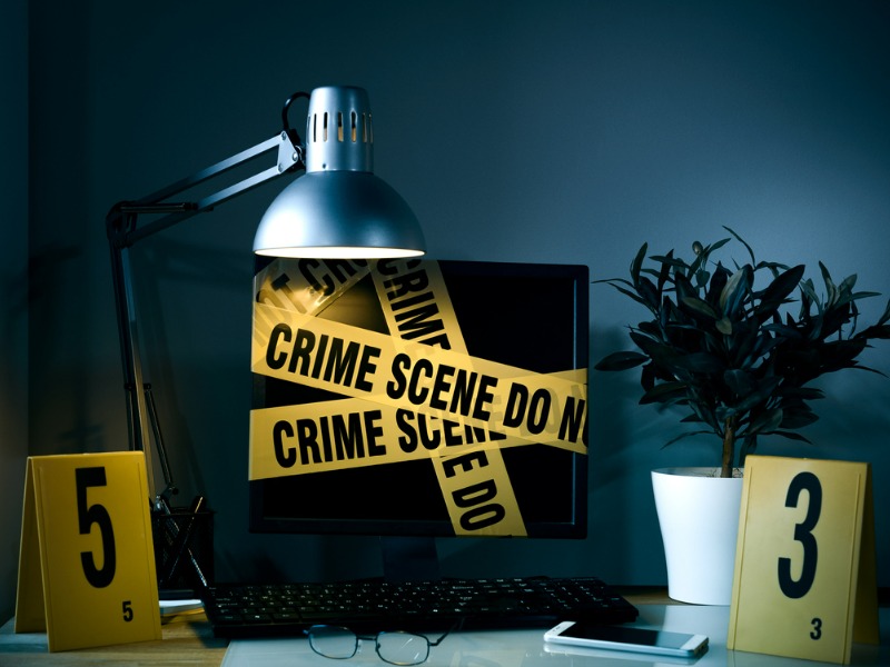 Computer wrapped with crime scene tape to represent a hacker attack