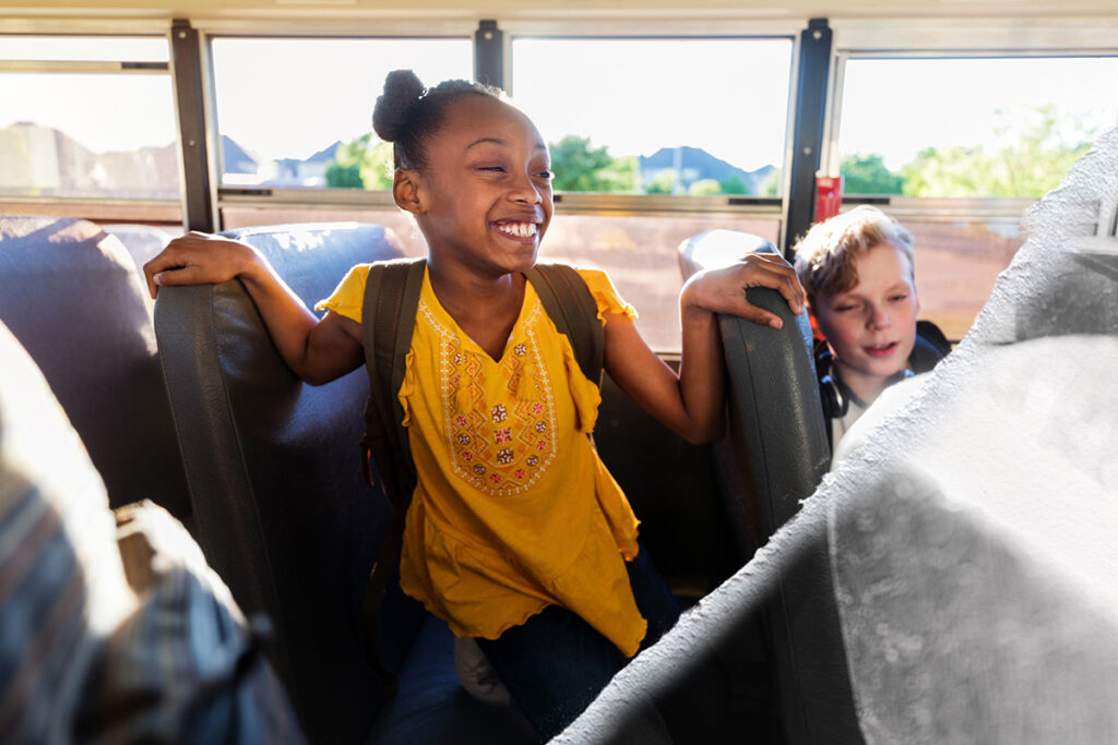 A girl smiles on a school bus.