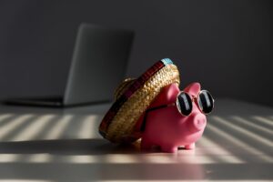 Piggy bank in sunglasses and sombrero with a laptop in the background