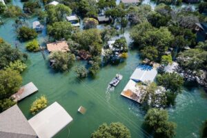 Water Rescue crew on site searching for survivors after dangerous NatCat Flooding Aerial drone views high above Flooding caused by Climate Change leaving entire neighborhood underwater and houses completely under water , boat with water rescue searching for people stuck in their flooded homes