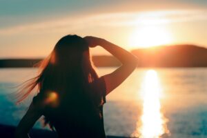 Woman looking out over the lake into the sunset in the horizon