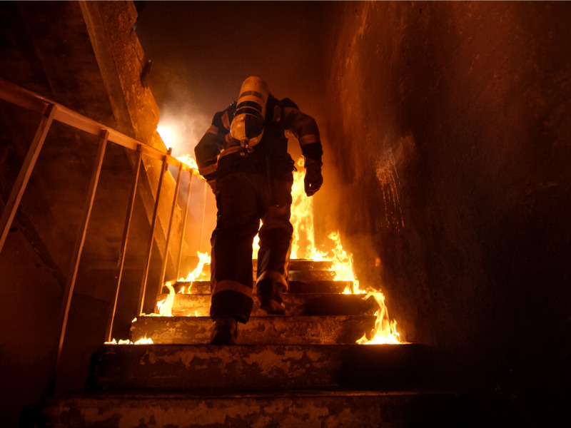 Firefighter heading up stairs in a burning home