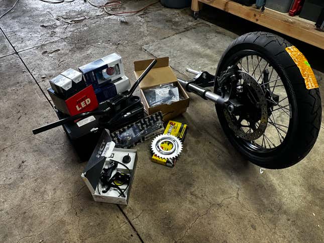 A pile of motorcycle parts sits on a garage floor.