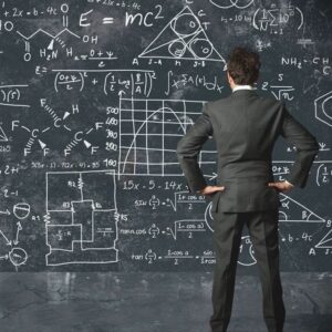 A businessman in a suit looking at a chalkboard of math