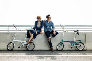 Young people posing on fence of bridge embracing near bicycles