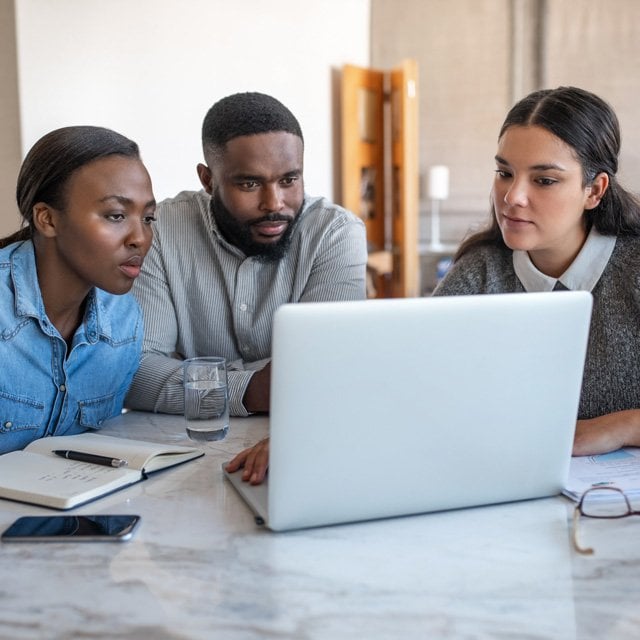 Advisor explaining to a couple, looking at laptop