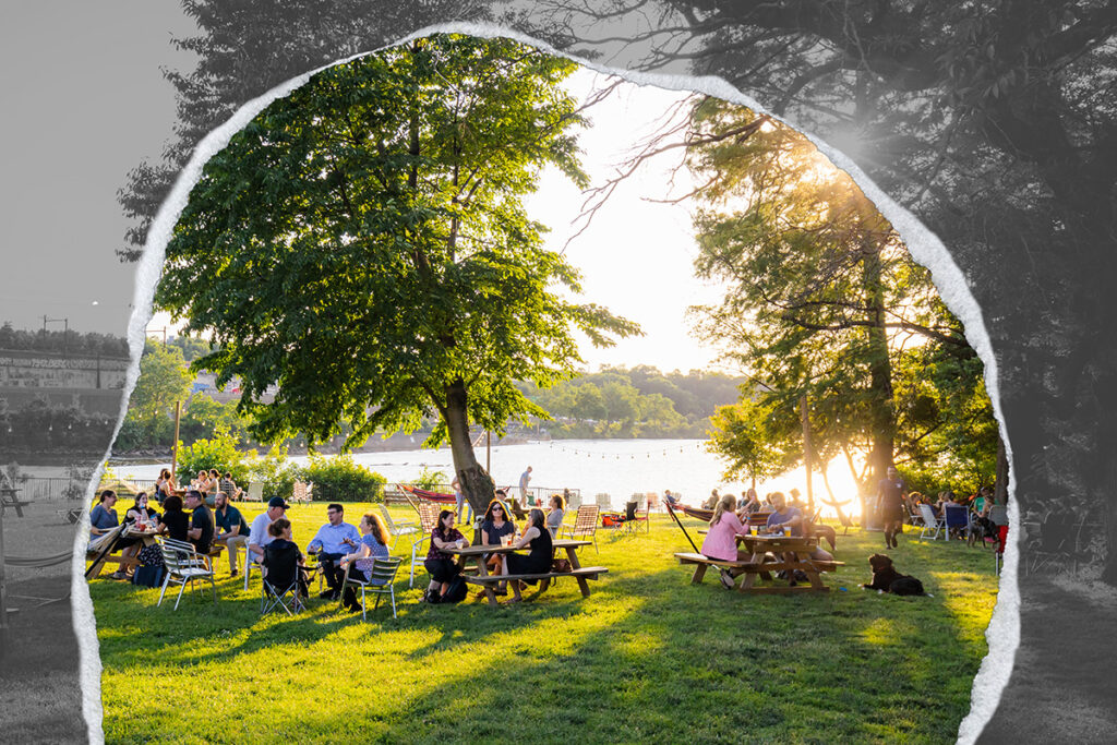 A group of people gather in a park along a river.