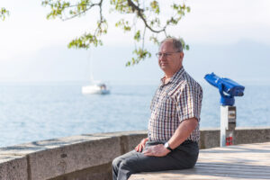 A photo of Jay Comfort sitting by the water outside.