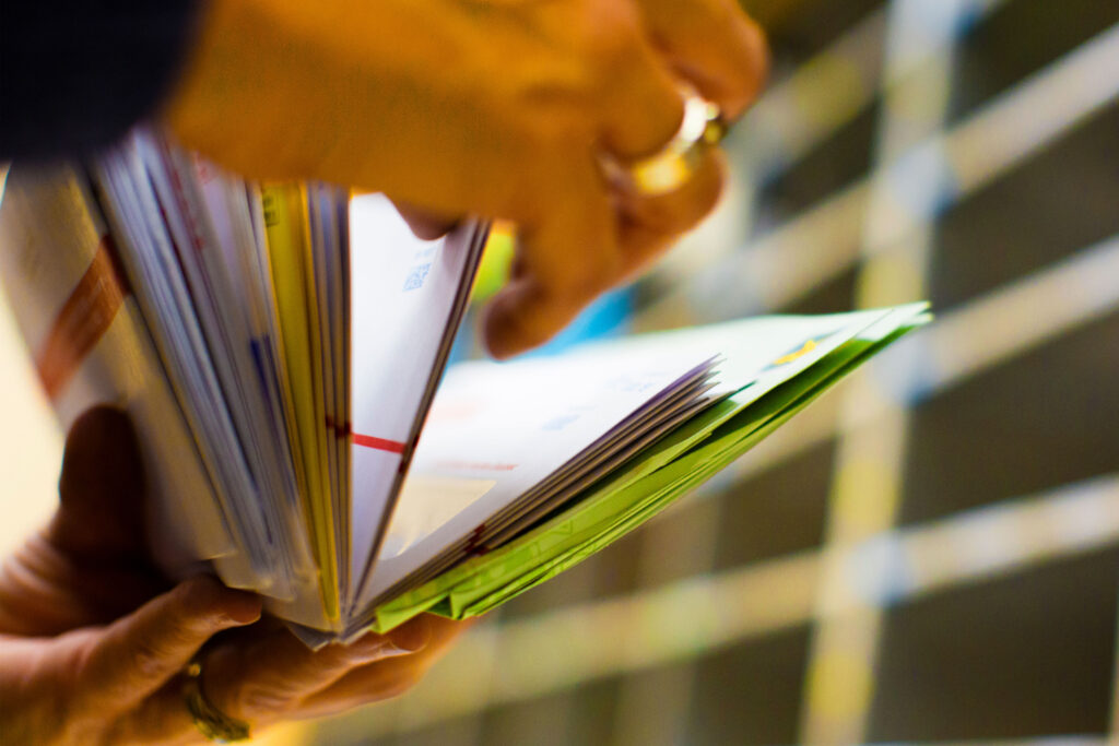 A photo of hands flipping through mail.