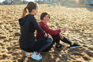 Young mother smiling and looking at her daughter after a running workout in the beach.