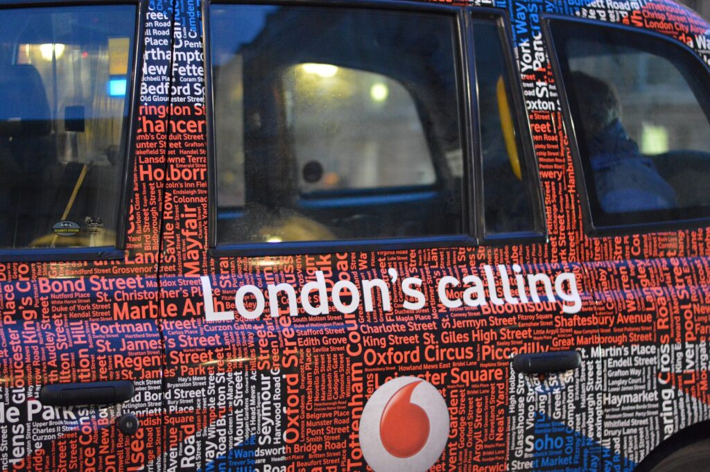 Close up of a side of a London Black cab with the words London's Calling written down the side.