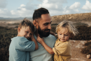 Little boys in their father's arms in highlands in the evening light