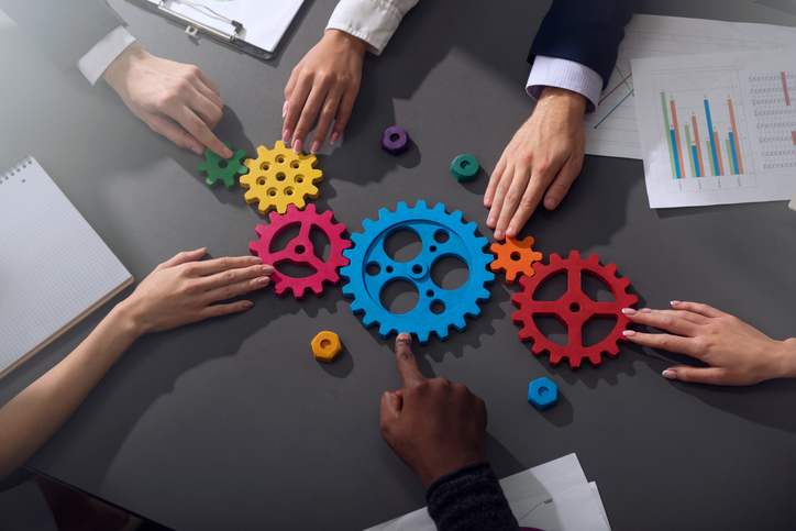 Teamwork of businesspeople work together and combine pieces of gears. Partnership and integration concept