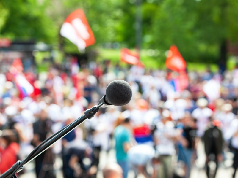 Microphone on a podium with blurred crowd of strikers in the background