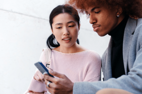 Two Gen Z consumers shopping clothes online using their mobile phone.