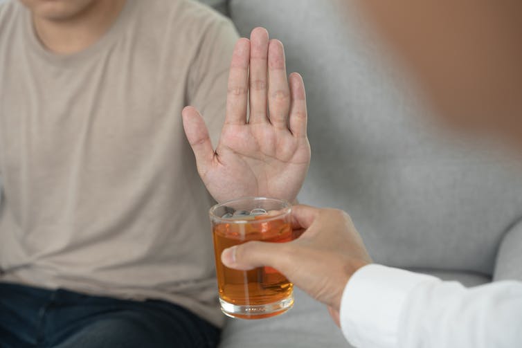 A man's hand refusing to take a glass.