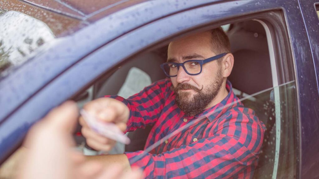 Man hands license to police officer - do speeding tickets affect car insurance