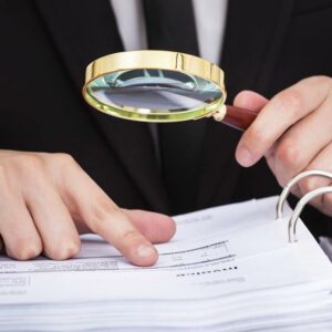 A businessman looking at data through a magnifying glass