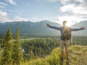 Hiker stretches arms out on mountain bluff, sunrise