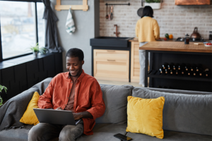 Husband smiling at laptop explaining to his wife the benefits of permanent life insurance