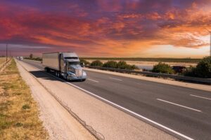 A long haul truck driving in the sunset