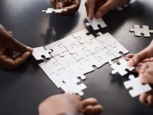 Many hands putting together a jigsaw puzzle