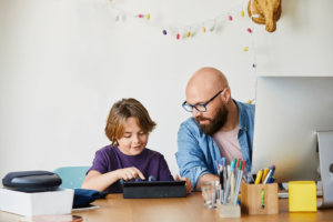 Smiling mid adult man looking at son using digital tablet at home