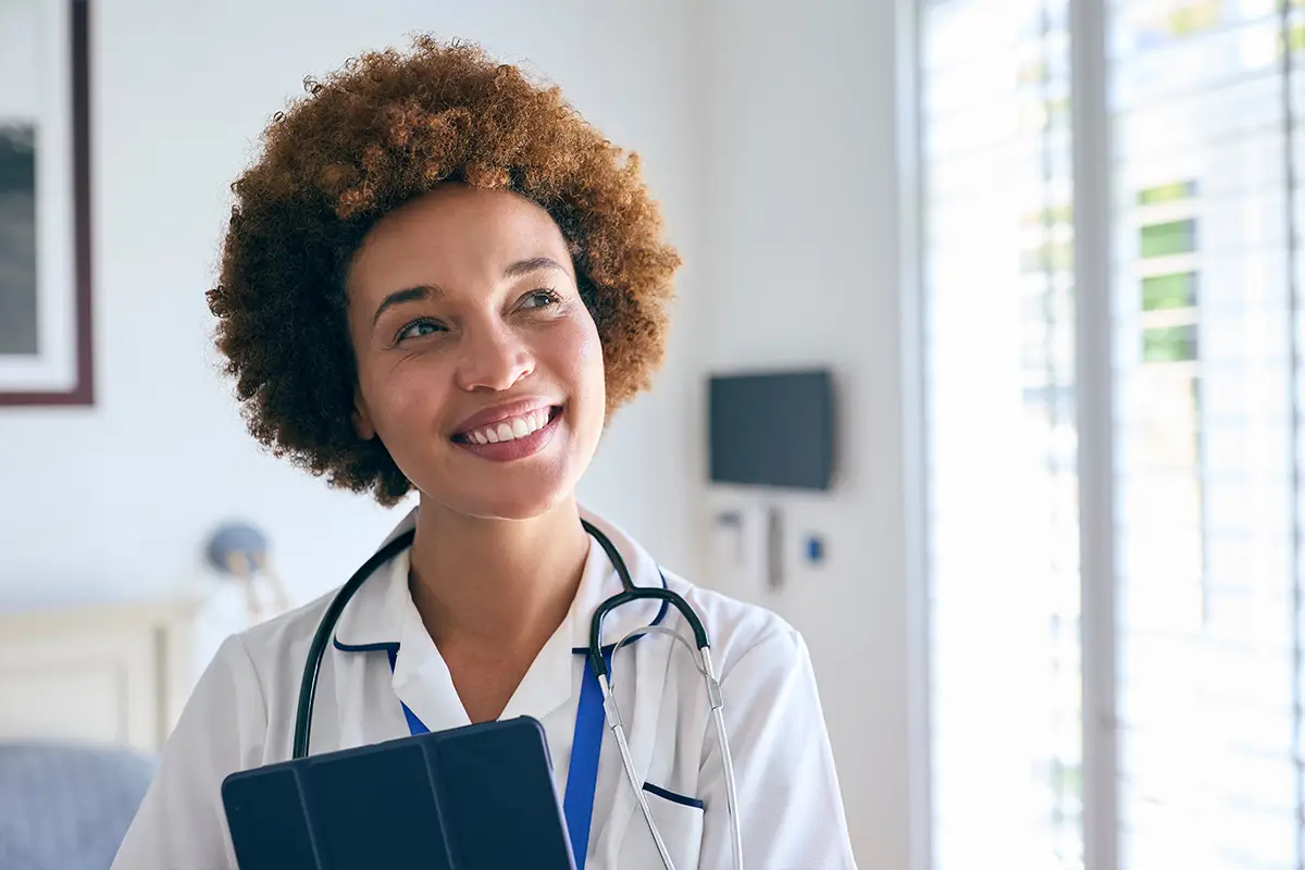 Portrait Of Smiling Female Nurse Wearing Uniform With Digital Tablet In Private Hospital Room