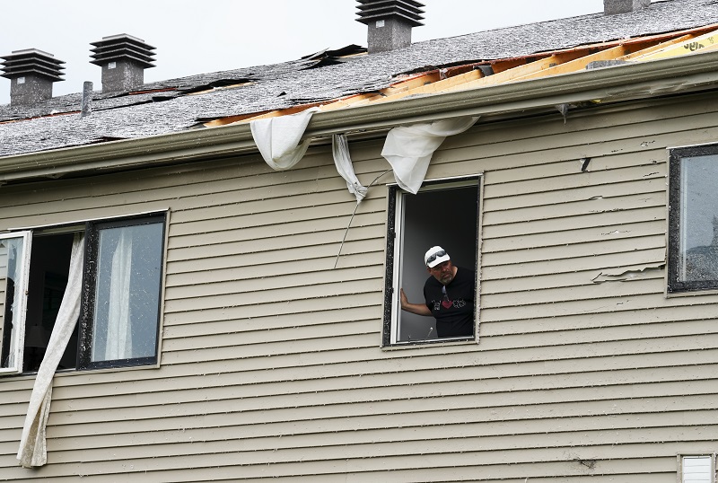 An Ottawa resident looking out a window of a tornado-damaged home