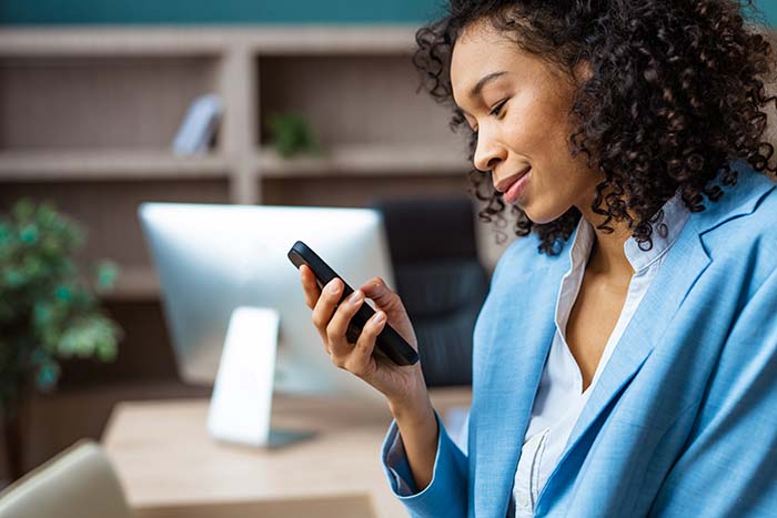 Businesswoman smiles at her phone while planning for retirement