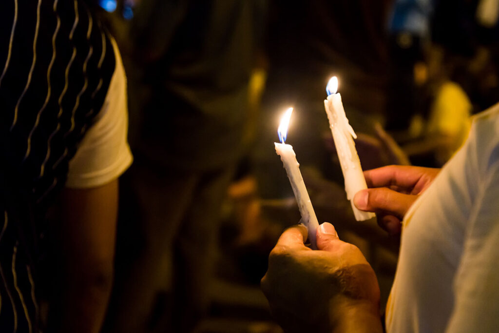 People holding a candlelight vigil in darkness