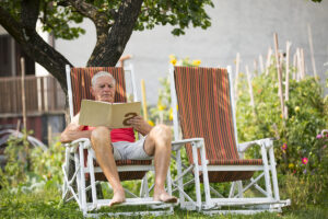 Senior Adult Man Reading a Book in Backyard