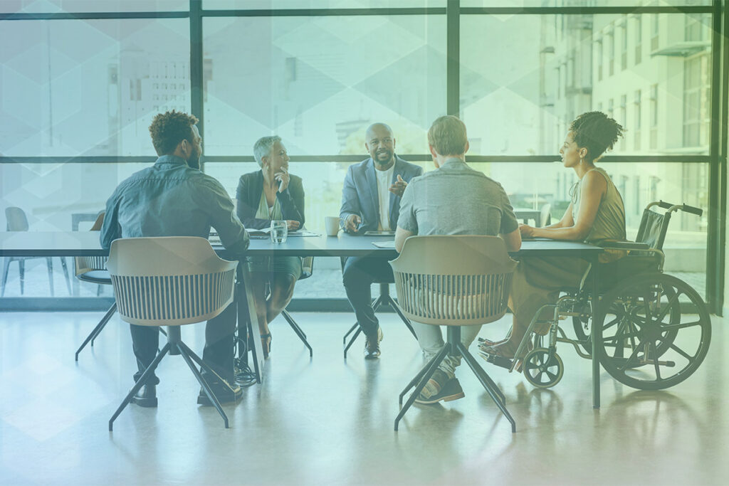 A group of people have a meeting in an office around a conference table.