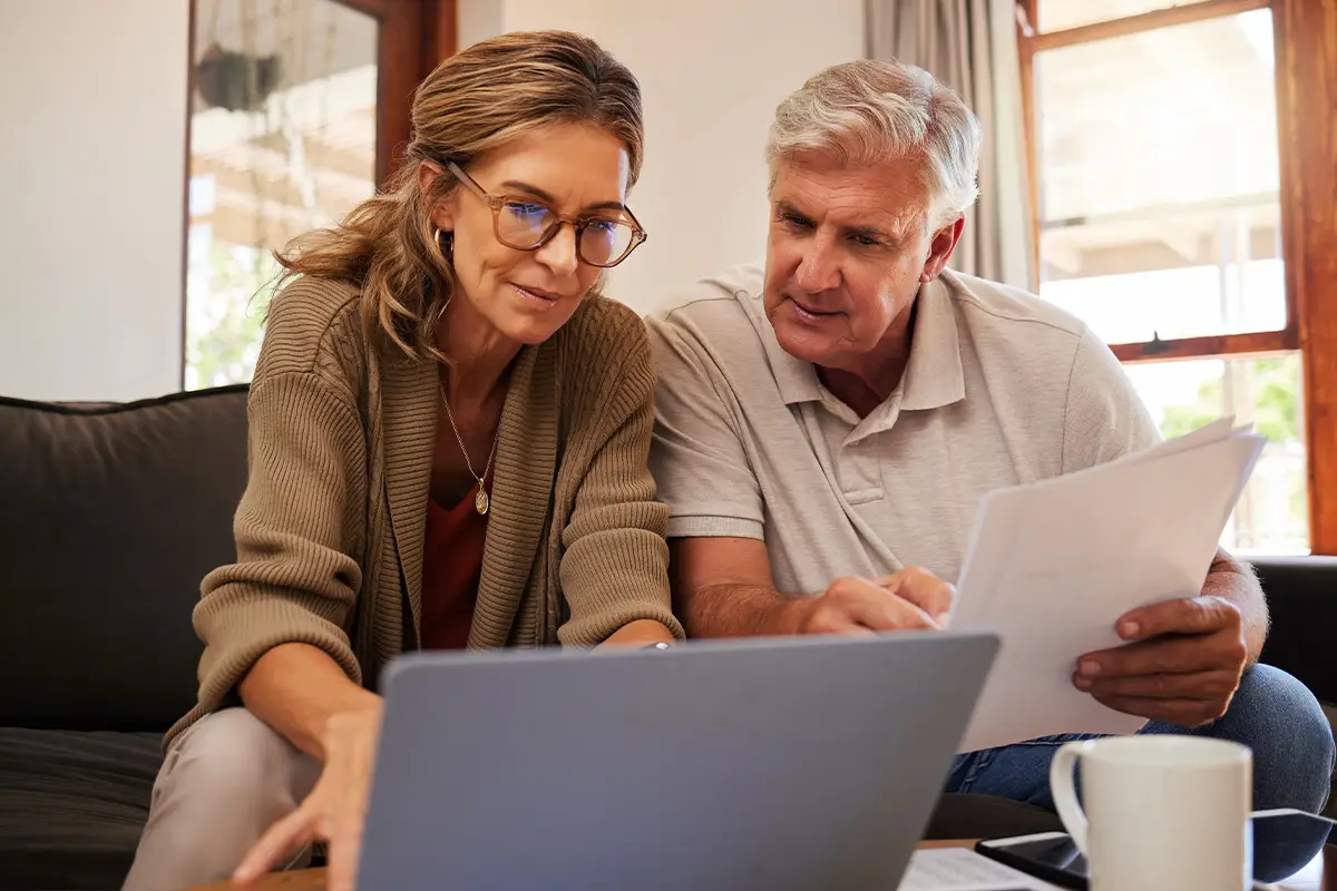 retired couple look at laptop together planning finances 