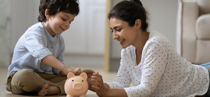mom and young male child putting coins in a piggy bank