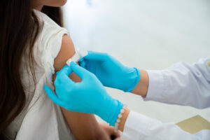 A doctor puts a bandage on a young girl's arm after she received a vaccine.